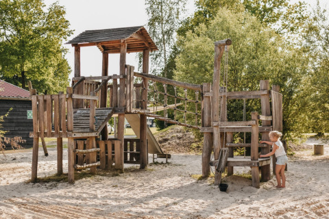 Holzspielplatz auf Camping De Rammelbeek in Overijssel, Niederlande, mit einem Kind beim Spielen.