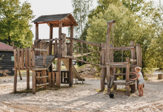 Holzspielplatz auf Camping De Rammelbeek in Overijssel, Niederlande, mit einem Kind beim Spielen.