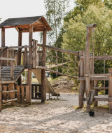 Parque infantil de madera en Camping De Rammelbeek, Overijssel, Países Bajos, con una niña jugando.