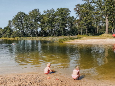 Zwei Kinder spielen am Seeufer im Ferienpark Camping De Rammelbeek, Overijssel, Niederlande, im Grünen.