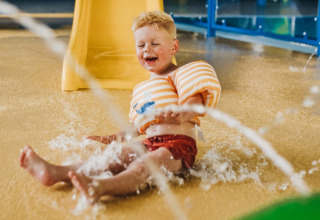 Un bambino con braccioli si diverte nell’area giochi d’acqua di Camping De Rammelbeek, Overijssel, Paesi Bassi.