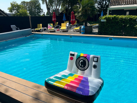 Piscina all'aperto al Camping Emmen, Drenthe, Paesi Bassi, con gonfiabile a forma di fotocamera e lettini.