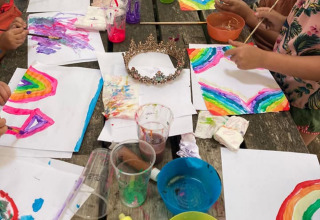 Bambini dipingono arcobaleni colorati a un tavolo di legno al Camping Emmen, villaggio vacanze Drenthe.