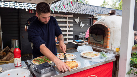 Uomo che prepara la pizza fresca in un forno a legna al Camping Emmen, un parco vacanze a Drenthe, Paesi Bassi.