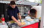Uomo che prepara la pizza fresca in un forno a legna al Camping Emmen, un parco vacanze a Drenthe, Paesi Bassi.
