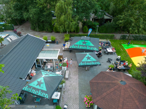 Vista aérea de zona de asientos al aire libre con sombrillas Heineken en Camping Emmen, Drenthe, Países Bajos.