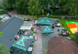 Luchtfoto van terras met Heineken-parasols bij Camping Emmen, vakantiepark in Drenthe, Nederland.