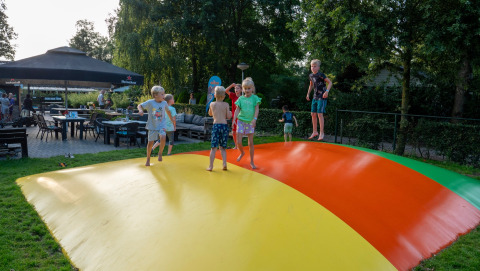 Bambini che giocano e saltano su un cuscino gonfiabile colorato al campeggio Emmen, parco vacanze in Drenthe, Paesi Bassi.