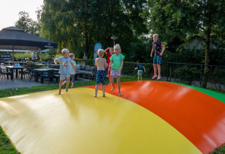 Bambini che giocano e saltano su un cuscino gonfiabile colorato al campeggio Emmen, parco vacanze in Drenthe, Paesi Bassi.