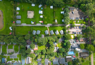 Vista aérea del parque vacacional Camping Emmen en Drenthe, Países Bajos, con tiendas y cabañas verdes.