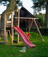 Área de juegos con tobogán y columpios en Camping Emmen, parque vacacional en Drenthe, Países Bajos.