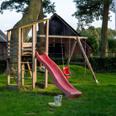 Área de juegos con tobogán y columpios en Camping Emmen, parque vacacional en Drenthe, Países Bajos.