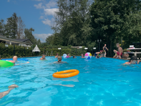 Niños jugando y nadando en la piscina exterior del Camping Emmen, un parque vacacional en Drenthe, Países Bajos.