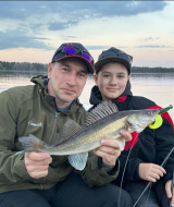 Two people holding a freshly caught fish while fishing on the lake at sunset at Camping Falkudden, Sweden.