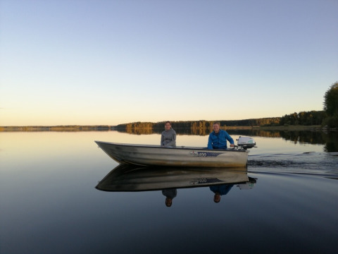 Two people ride in a small boat on a calm lake at Camping Falkudden holiday park in Dalarna, Sweden.