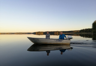 Two people ride in a small boat on a calm lake at Camping Falkudden holiday park in Dalarna, Sweden.
