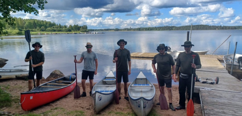 Cinque persone con canoe sulla riva di un lago al Camping Falkudden, parco vacanze in Dalarna, Svezia.
