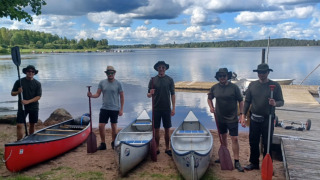 Cinco personas junto a tres canoas en la orilla de un lago en Camping Falkudden, Dalarna, Suecia.