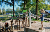 Et barn leger ved en vandpumpe på en solrig dag i Familiepark de Vechtvallei, Overijssel, Holland.