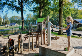 Ein Kind spielt bei sonnigem Wetter an einer Wasserpumpe im Familiepark de Vechtvallei, Overijssel.