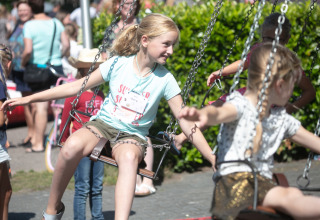 Children enjoying a swing ride at Familiepark de Vechtvallei, a holiday park in Overijssel, Netherlands.
