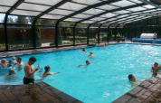 Indendørs swimmingpool i Familiepark de Vechtvallei, Holland, fyldt med glade feriegæster og børn leger.