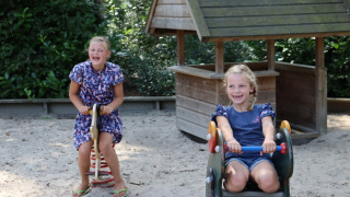 Dos niñas sonrientes juegan en balancines de un parque de arena en Familiepark de Vechtvallei, Overijssel.