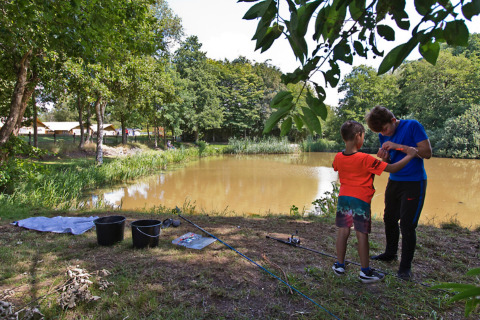Deux personnes pêchent près d’un lac au Familiepark de Vechtvallei, Overijssel, entourés de verdure.