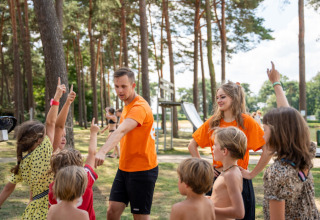 Children and two camp leaders interacting at an outdoor playground in Familiepark Goolderheide, Limburg, Belgium.