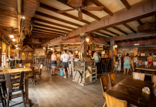 Ristorante interno con arredi in legno e ospiti al parco vacanze Familiepark Goolderheide, Limburgo, Belgio.