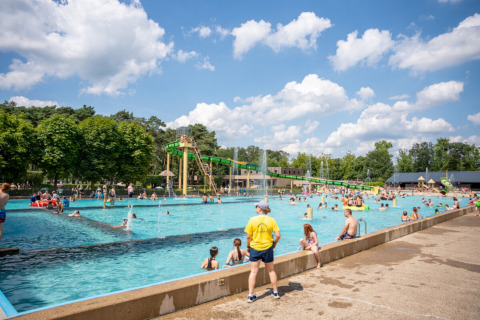 People enjoy a sunny day at an outdoor swimming pool with water slides in Familiepark Goolderheide, Belgium.