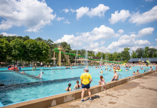 Menschen genießen einen sonnigen Tag am Außenpool mit Wasserrutschen im Familiepark Goolderheide, Belgien.