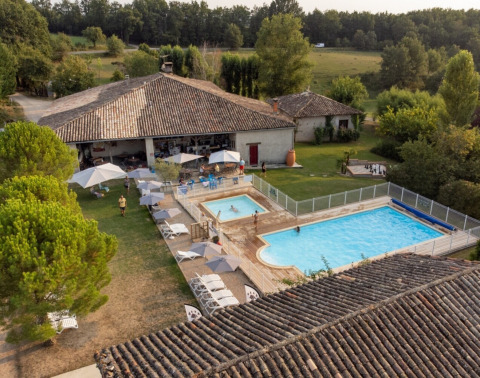 Vista aérea de Camping Fargogne en Occitania, Francia, con piscinas y huéspedes disfrutando al aire libre.