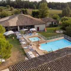 Vista aérea de Camping Fargogne en Occitania, Francia, con piscinas y huéspedes disfrutando al aire libre.