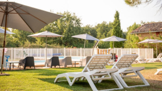 Tumbonas y sombrillas junto a la piscina en Camping Fargogne, un parque vacacional en Occitania, Francia.