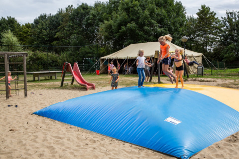 Niños jugando sobre un cojín inflable y un tobogán en Camping Gorishoek, un parque vacacional en Zeeland