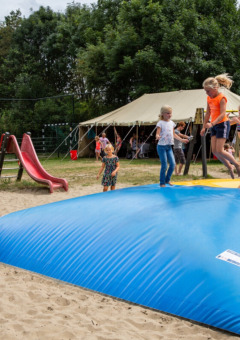 Kinder spielen auf einem Hüpfkissen und einer Rutsche auf dem Spielplatz von Camping Gorishoek, Zeeland