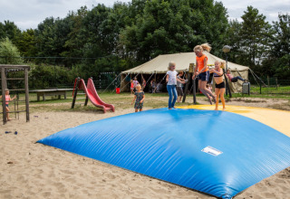 Kinder spielen auf einem Hüpfkissen und einer Rutsche auf dem Spielplatz von Camping Gorishoek, Zeeland