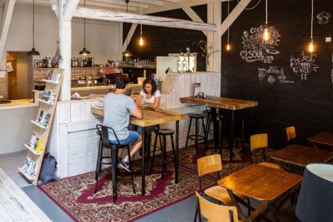 Gemütlicher Cafébereich im Camping Gorishoek in Zeeland, Niederlande mit Holztischen und Wanddeko.