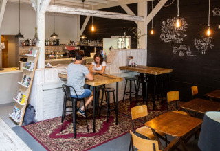 Et hyggeligt caféområde på Camping Gorishoek i Zeeland, Nederlandene med borde, stole og dekoration.