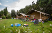 Familievenlige telte og campingområde med legetøj og stole på Camping Gorishoek, Zeeland, Holland, om sommeren.