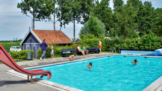 Außenpool mit Kindern und Erwachsenen im Camping Gorishoek, Zeeland, Niederlande, umgeben von Bäumen.