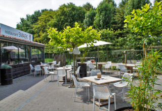 Terrasse extérieure du restaurant SMAEK au Camping Gorishoek, Zélande, Pays-Bas, entourée de verdure.