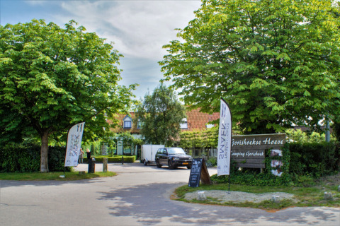 Indkørsel til Camping Gorishoek feriepark i Zeeland, Holland, omgivet af grønne træer og skilte.