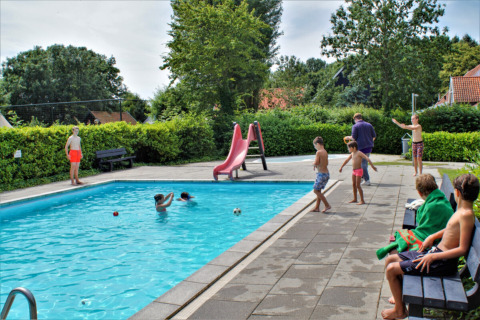 Niños jugando y nadando en la piscina de Camping Gorishoek, parque vacacional en Zelanda, Países Bajos.