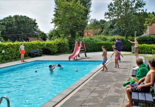 Kinder spielen am Pool im Ferienpark Camping Gorishoek in Zeeland, Niederlande, umgeben von Grün.