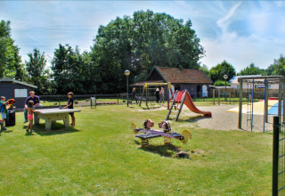 Children play on the playground at Camping Gorishoek holiday park in Zeeland, Netherlands, with slides and games.