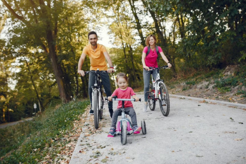 Familia paseando en bicicleta por un sendero en Camping het Swinnenbos, Brabante Flamenco, Bélgica.