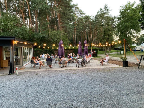 Outdoor dining area at Camping het Swinnenbos, with guests enjoying a summer evening in Belgium.