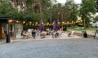 Buitenterras van Camping het Swinnenbos met gasten die genieten van de zomeravond in België.